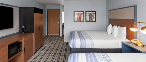 A hotel room with a bed, a TV, a desk with a lamp, and a microwave.