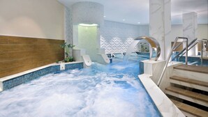 A hot tub with a waterfall feature, surrounded by a tiled area with a wooden bench and a staircase. - Amman Marriott Hotel (Amman)