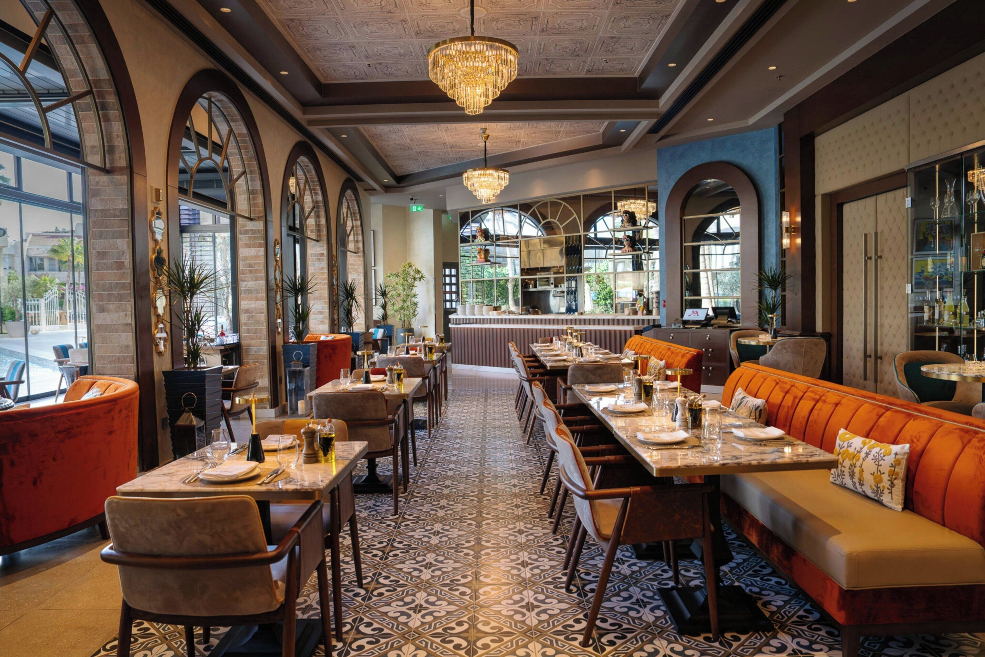 A restaurant with a long dining area, multiple tables, and a central seating area with a bench.