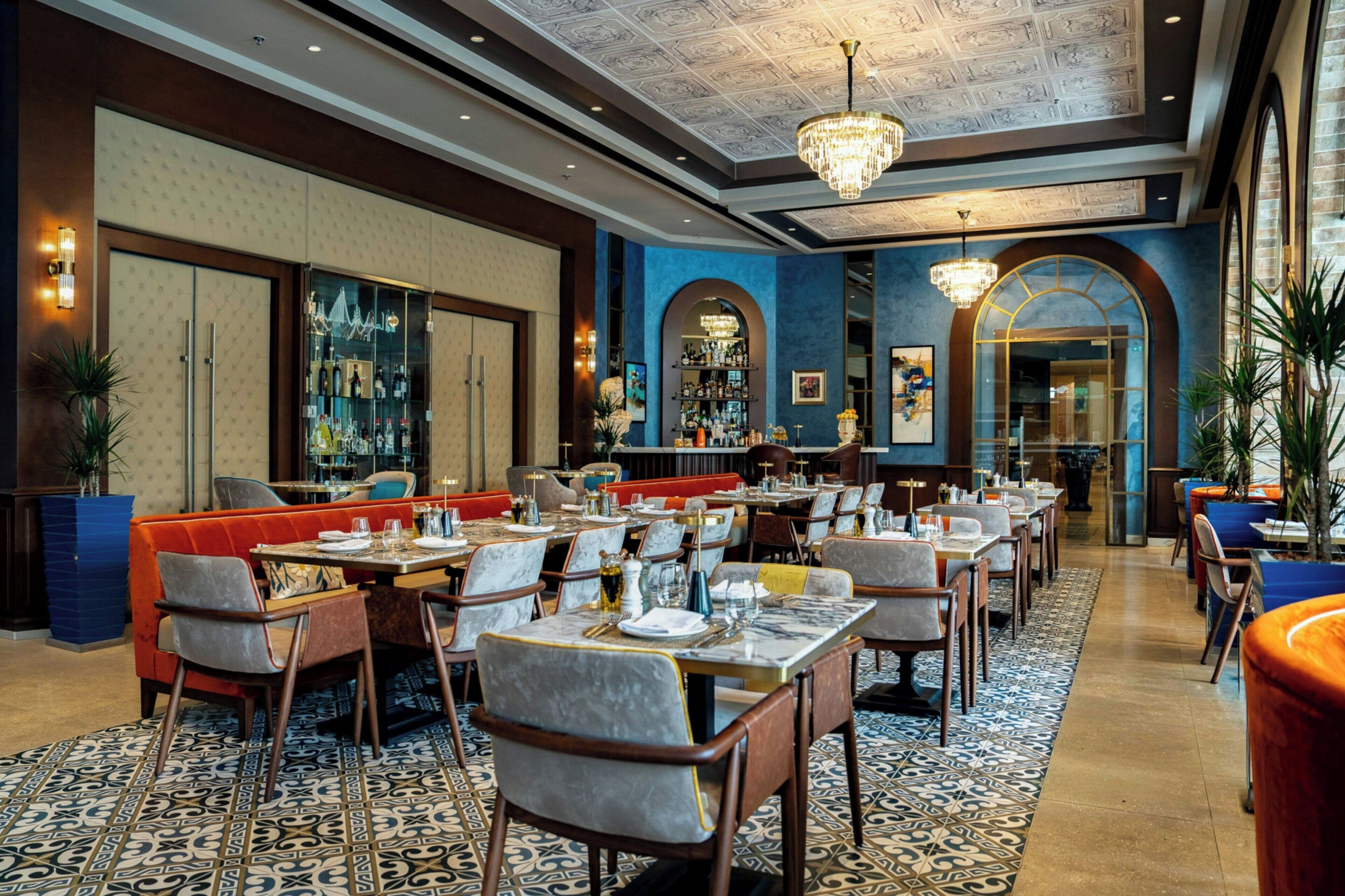 Un restaurante con varias mesas, sillas y una zona de bar.