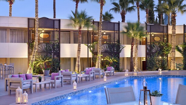 A poolside area with lounge chairs, a pool, and palm trees. - Amman Marriott Hotel (Amman)