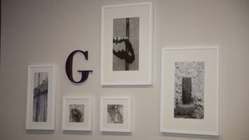Una pared con obras de arte enmarcadas y una gran letra 'G'.