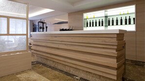 Una moderna recepción con detalles de madera, una vitrina de vidrio con botellas y un diseño minimalista.