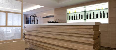 Una moderna recepción con detalles de madera, una vitrina de vidrio con botellas y un diseño minimalista.