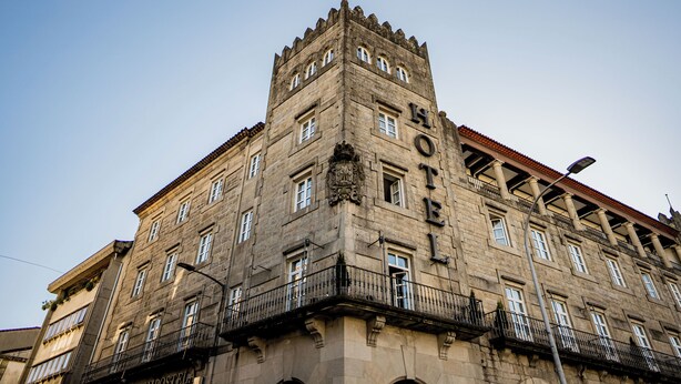 Un edificio histórico con una torre destacada y varios balcones.