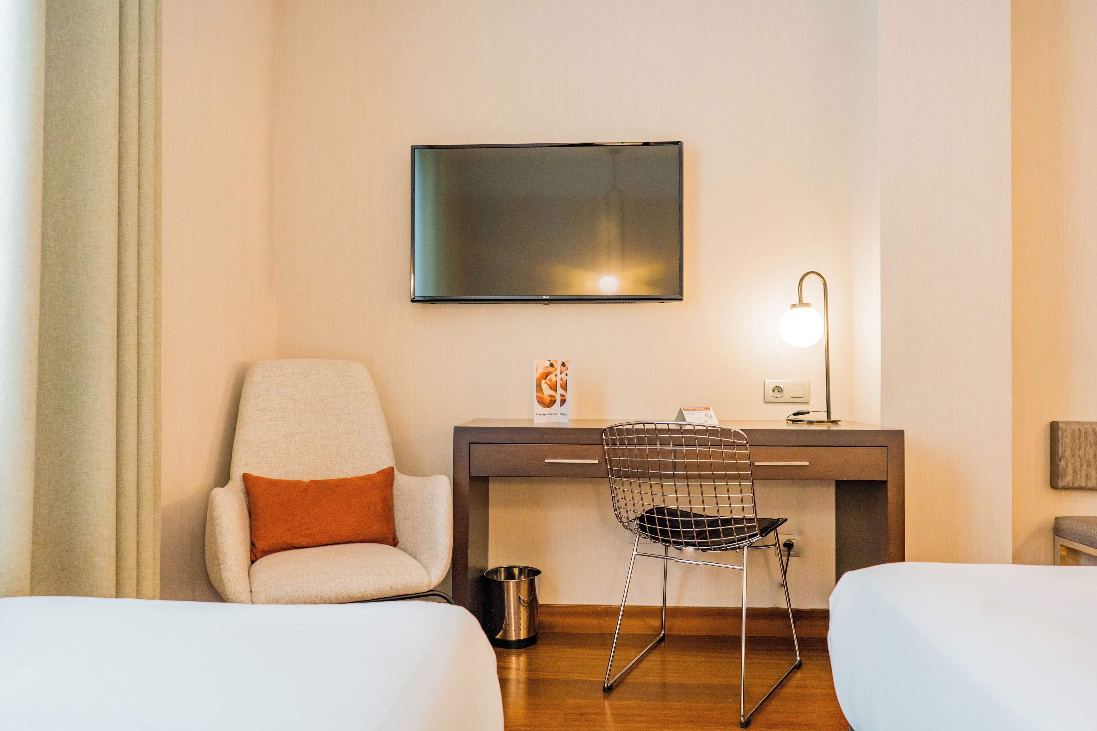Ein Hotelzimmer mit einem Bett, einem Schreibtisch mit Stuhl, einem Fernseher und einer Lampe.