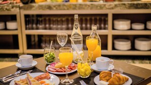 Un bufé de desayuno con diversos alimentos, bebidas y cubiertos sobre una mesa.