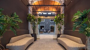 A hallway with two sofas, potted plants, and a reception area with a modern design. - Hesperia Barri Gòtic (Barcelona)