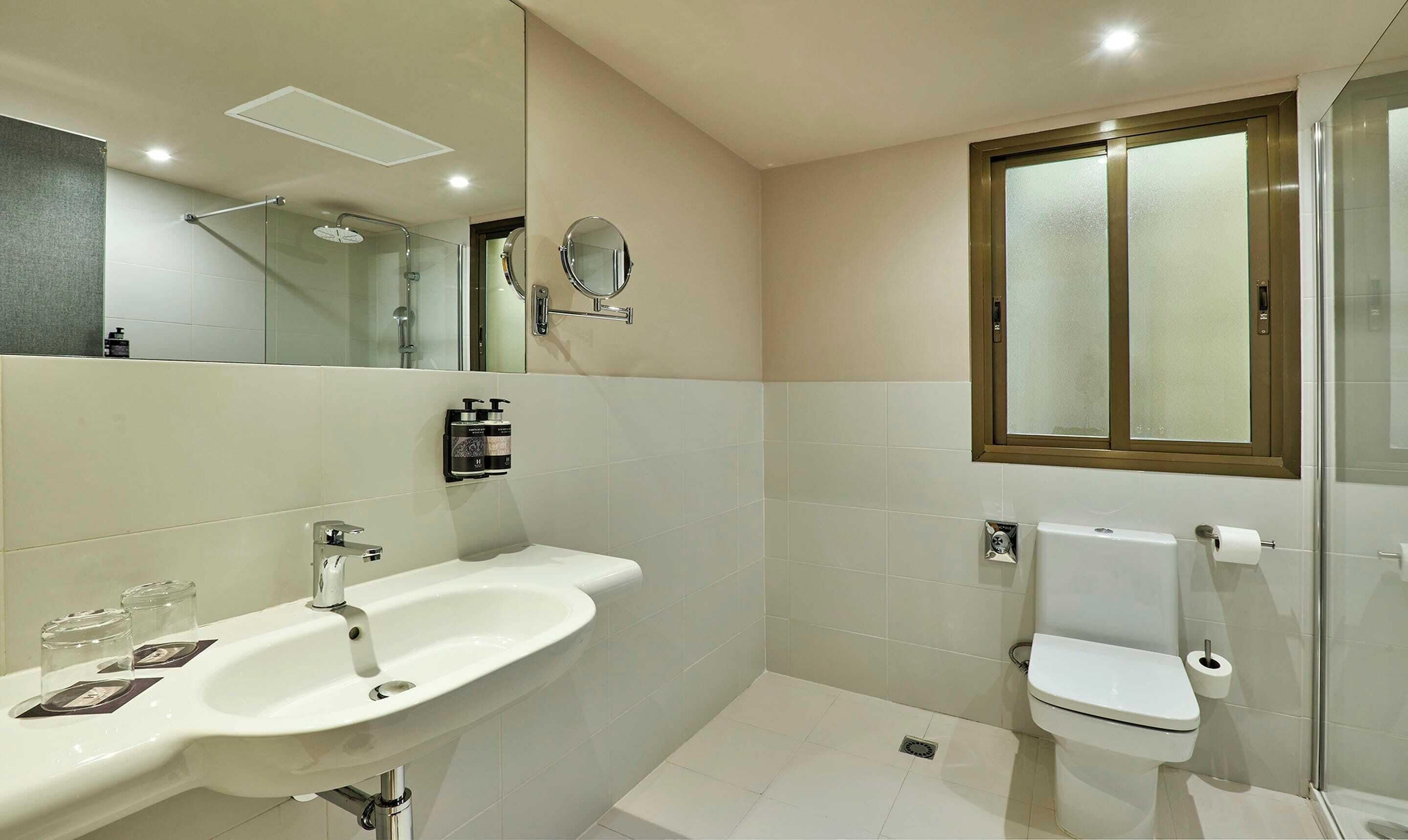 Une salle de bain moderne avec un lavabo, un miroir et des toilettes, le tout de couleur blanche.