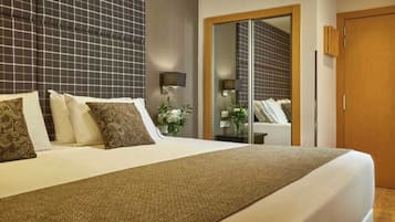 Una habitación de hotel con una cama grande, un armario, un espejo y una pequeña mesa con una planta.