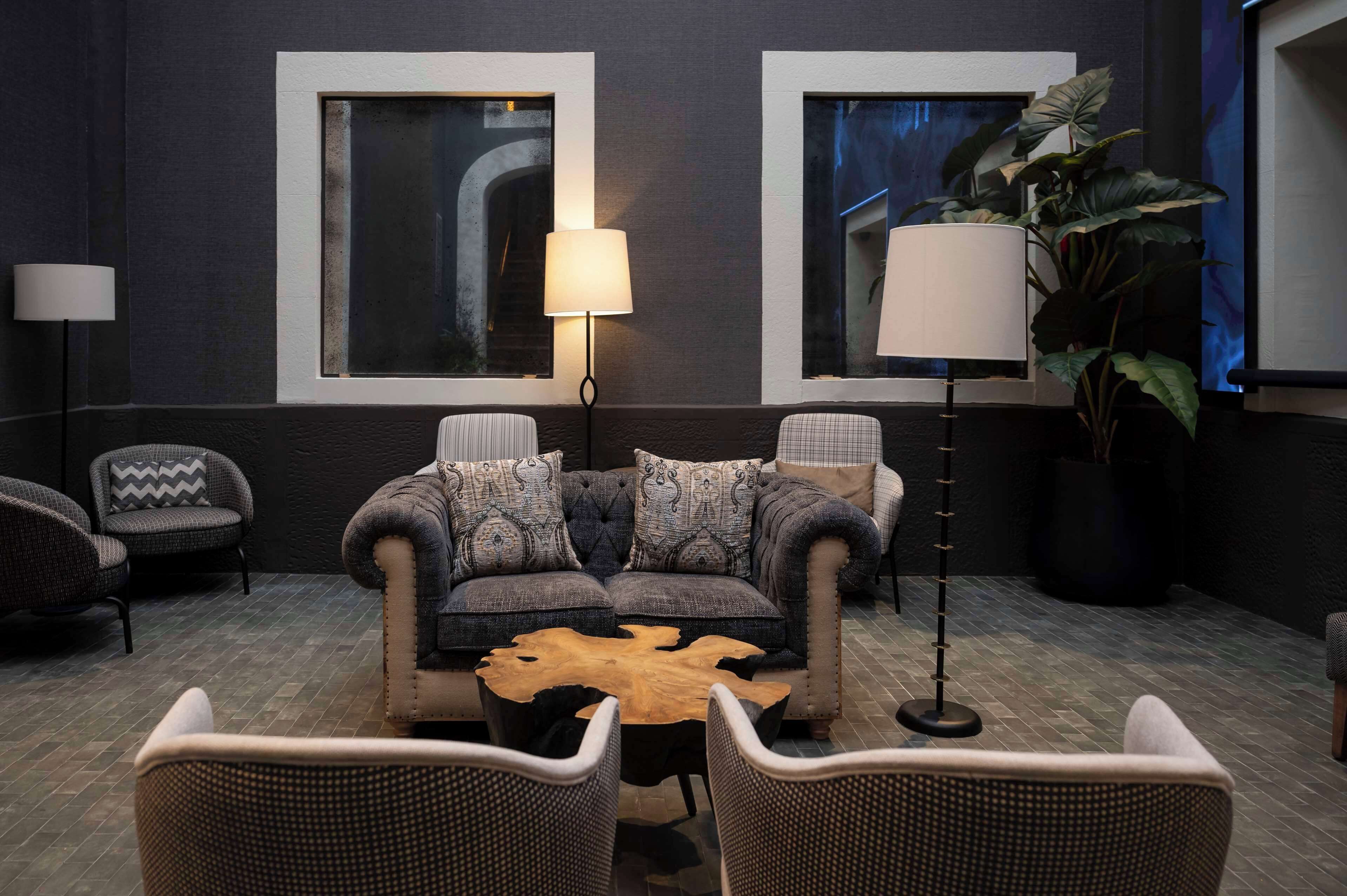 A modern lounge area with a sofa set, two floor lamps, and a large potted plant.