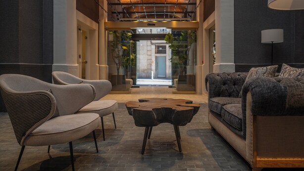 A lobby with a modern design, featuring a sofa, chairs, and a unique wooden coffee table. - Hesperia Barri Gòtic (Barcelona)