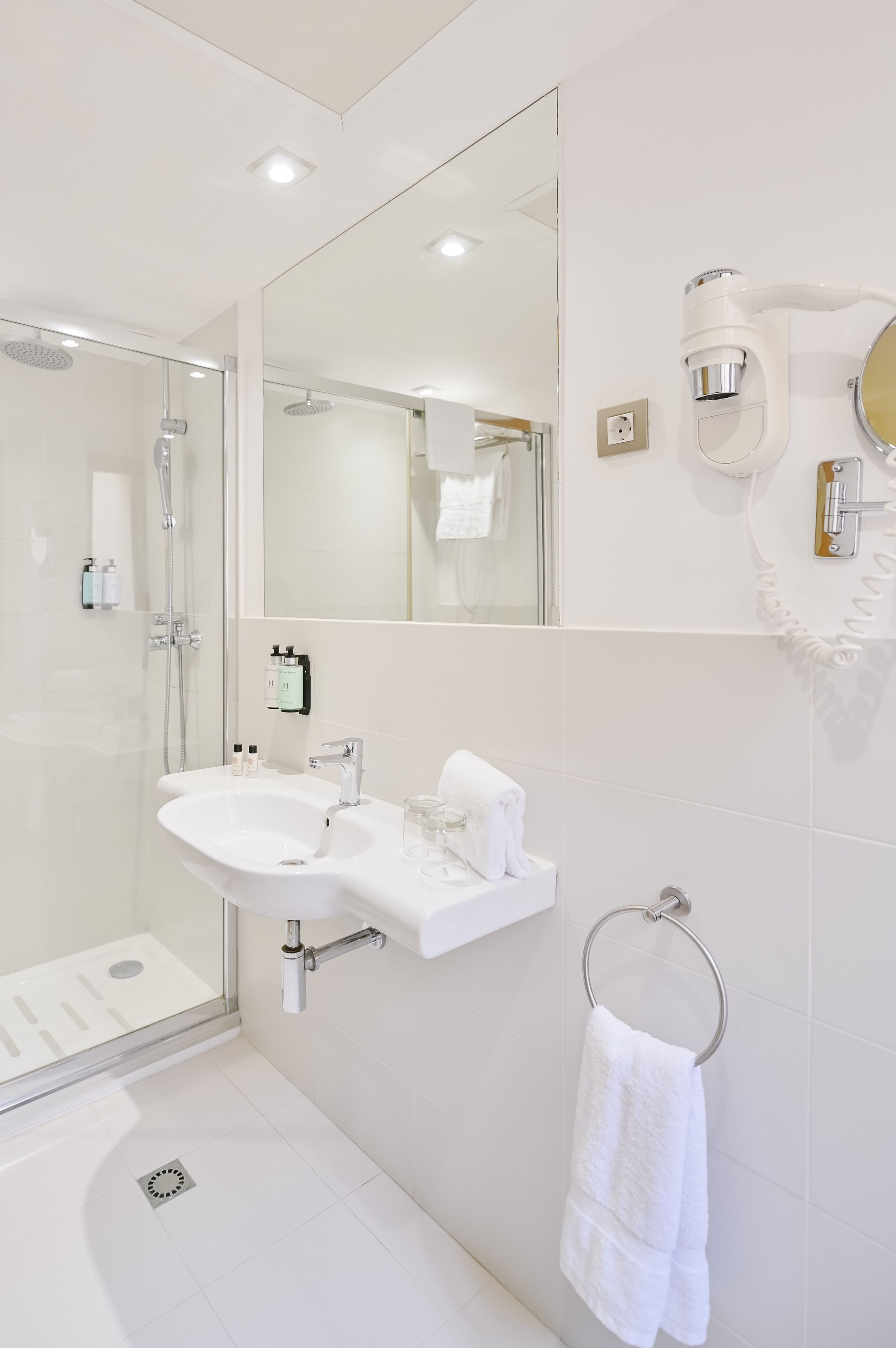 A modern bathroom with a glass-enclosed shower, a white sink, and a large mirror.