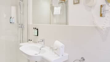 A modern bathroom with a glass-enclosed shower, a white sink, and a large mirror.