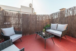 A patio area with wicker furniture, a glass coffee table, and a potted plant. - Hesperia Barri Gòtic (Barcelona)