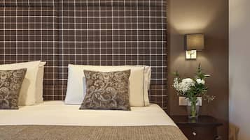 Una cama bien hecha con dos almohadas, una mesita de noche con un florero y una pared con un diseño texturizado.