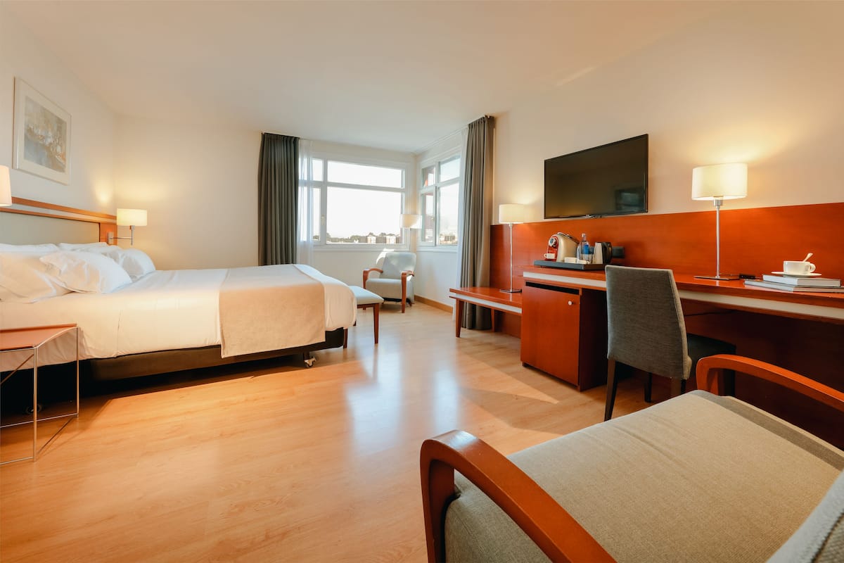 Una habitación de hotel con cama, escritorio, silla y televisor.