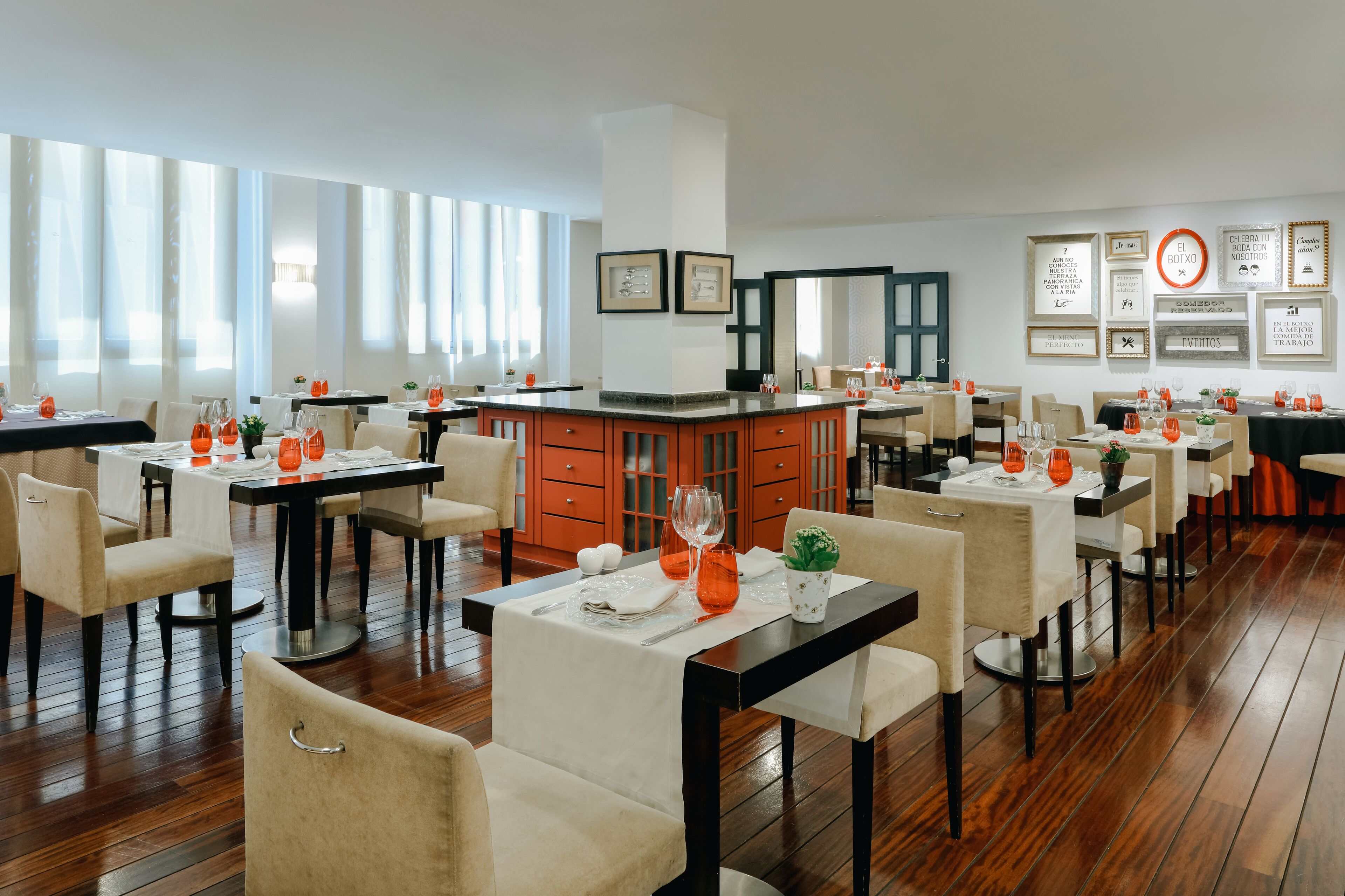 A spacious dining area with multiple tables and chairs, a central bar, and framed motivational quotes on the walls.