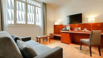 Een moderne hotelkamer met een bank, een bureau, een stoel en een televisie.