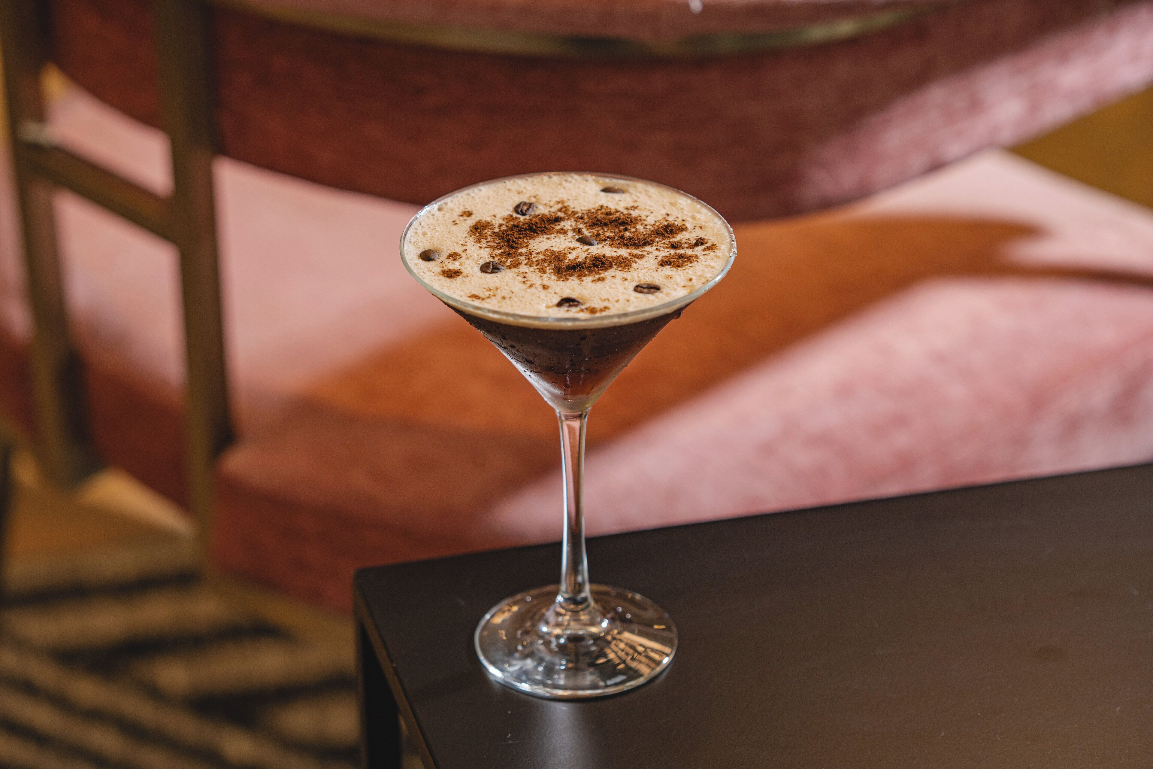 Una copa de martini con espuma sobre una mesa negra.