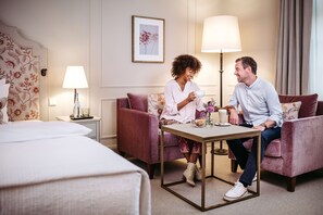 Una habitación de hotel con una cama, un sofá, una mesita y una lámpara.
