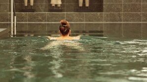 Una persona en una piscina con una pared de azulejos que muestra tres estatuas.