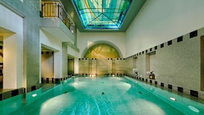 Una gran piscina cubierta con techo alto y tragaluz de vitral.