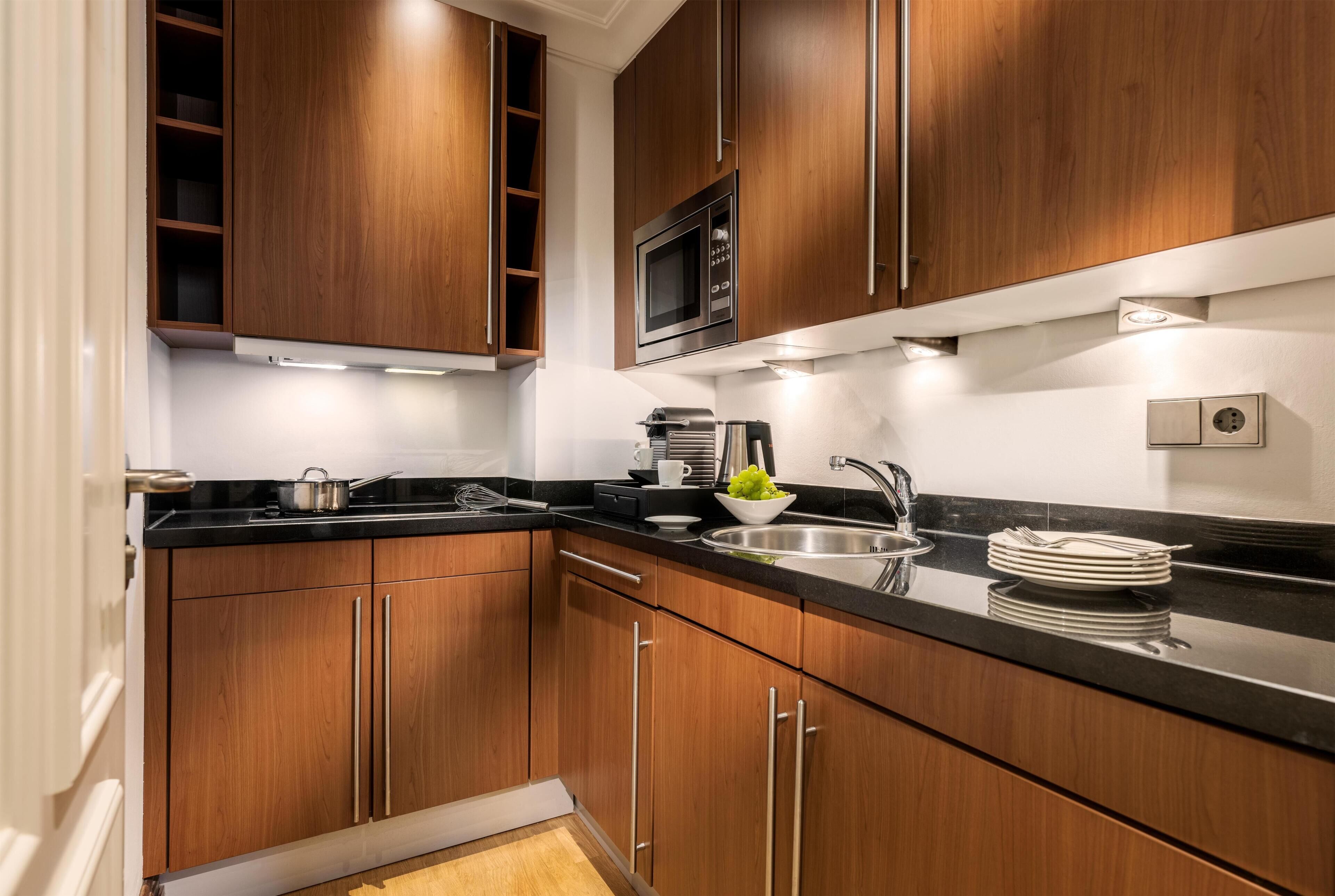 Una cocina moderna con armarios de madera, un lavamanos de acero inoxidable y un microondas.
