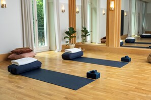 A yoga room with wooden flooring, yoga mats, and cushions.