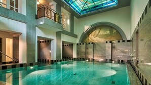 Una piscina interior amplia con techo alto y tragaluz de vidrieras.