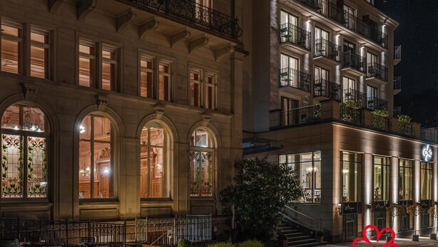 Un edificio histórico con ventanas de arco y una escalera que lleva a la entrada.