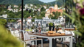 Una terraza con mesa lista para comer, con vistas a un pueblo con una iglesia y colinas.
