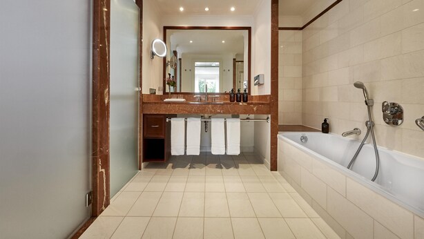 A modern bathroom with a large mirror, a bathtub, and a vanity with a sink.