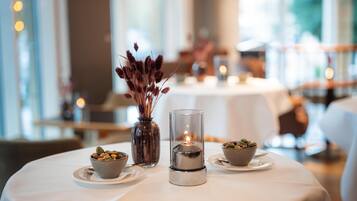 Une table dressée avec une bougie, un vase contenant des plantes séchées et deux petits bols remplis de noix.