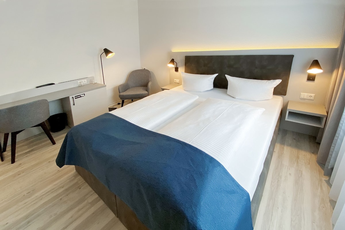Una habitación de hotel moderna con una cama grande, un escritorio y una silla.