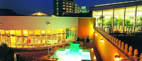 Un hotel con piscina, zona de estar al aire libre y vista a un edificio alto al fondo.