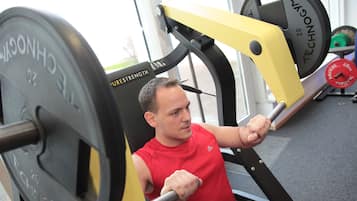 Un hombre ejercitándose en una máquina de gimnasio con pesas.