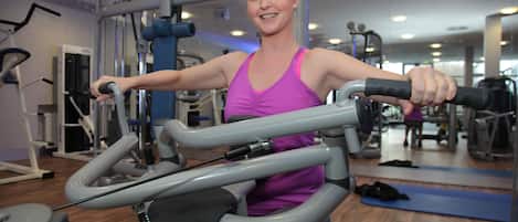 A gym with exercise equipment, a mirror, and a wooden floor.