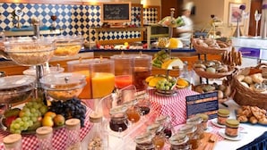 A buffet with various food items, including fruits, breads, and condiments.