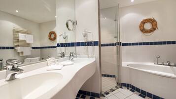 A modern bathroom with two sinks, a glass shower enclosure, and a bathtub.