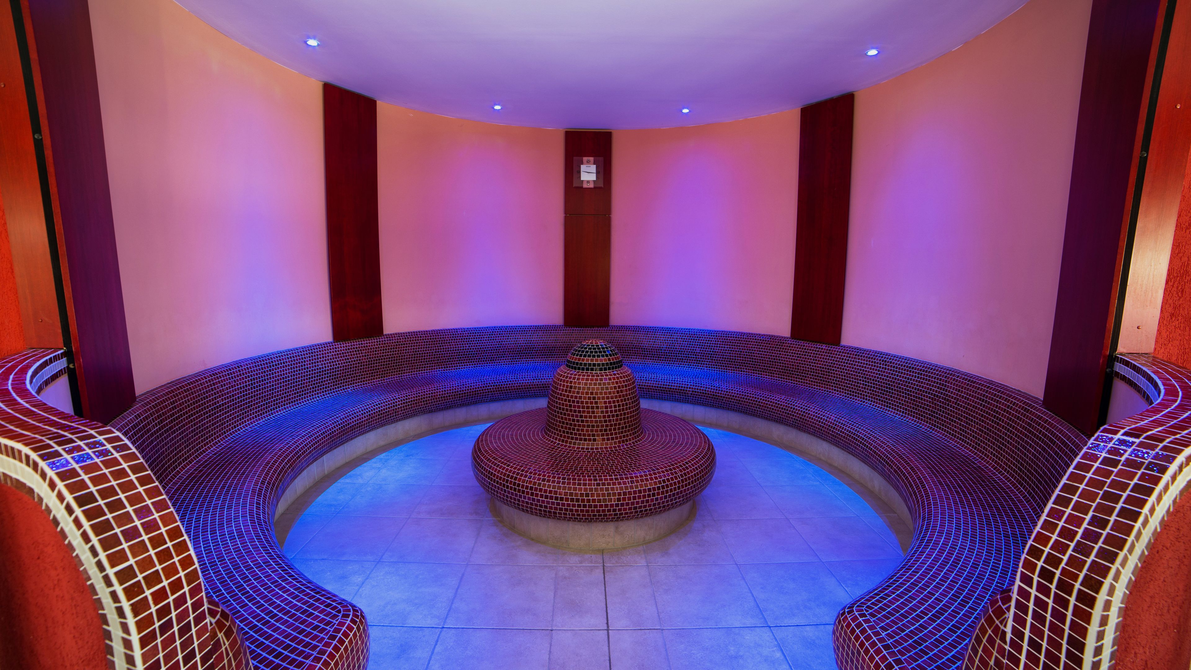 A circular hot tub area with tiled walls and a central fountain.