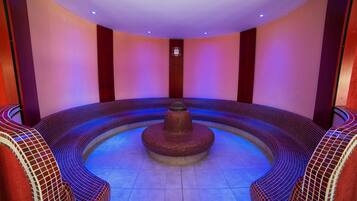A circular hot tub area with tiled walls and a central fountain.