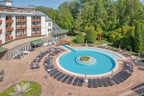 A hotel with a circular pool, sun loungers, and a landscaped garden. - Lotus Therme Hotel & Spa (Hévíz)