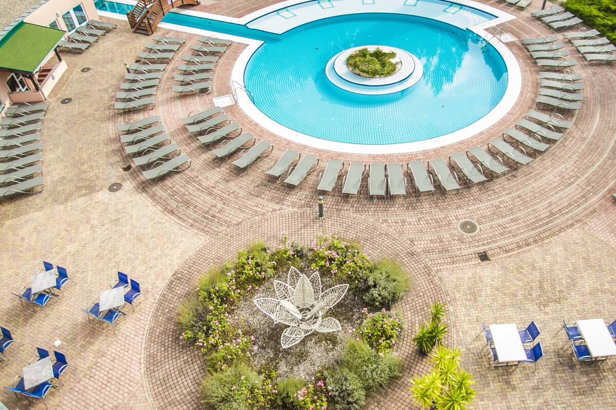 Ein Poolbereich mit Liegestühlen und einem zentralen Garten.