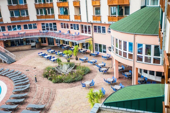 A hotel courtyard with outdoor seating, a pool, and multiple balconies. - Lotus Therme Hotel & Spa (Hévíz)