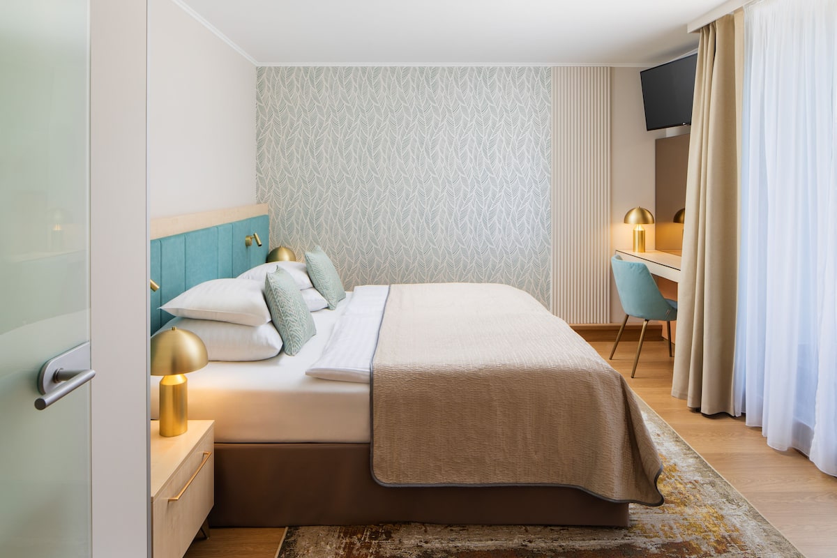 Ein modernes Hotelzimmer mit Bett, Schreibtisch und Fernseher.