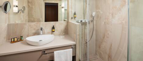 Un baño moderno con un espejo grande, un lavabo blanco y una ducha con mampara de vidrio.