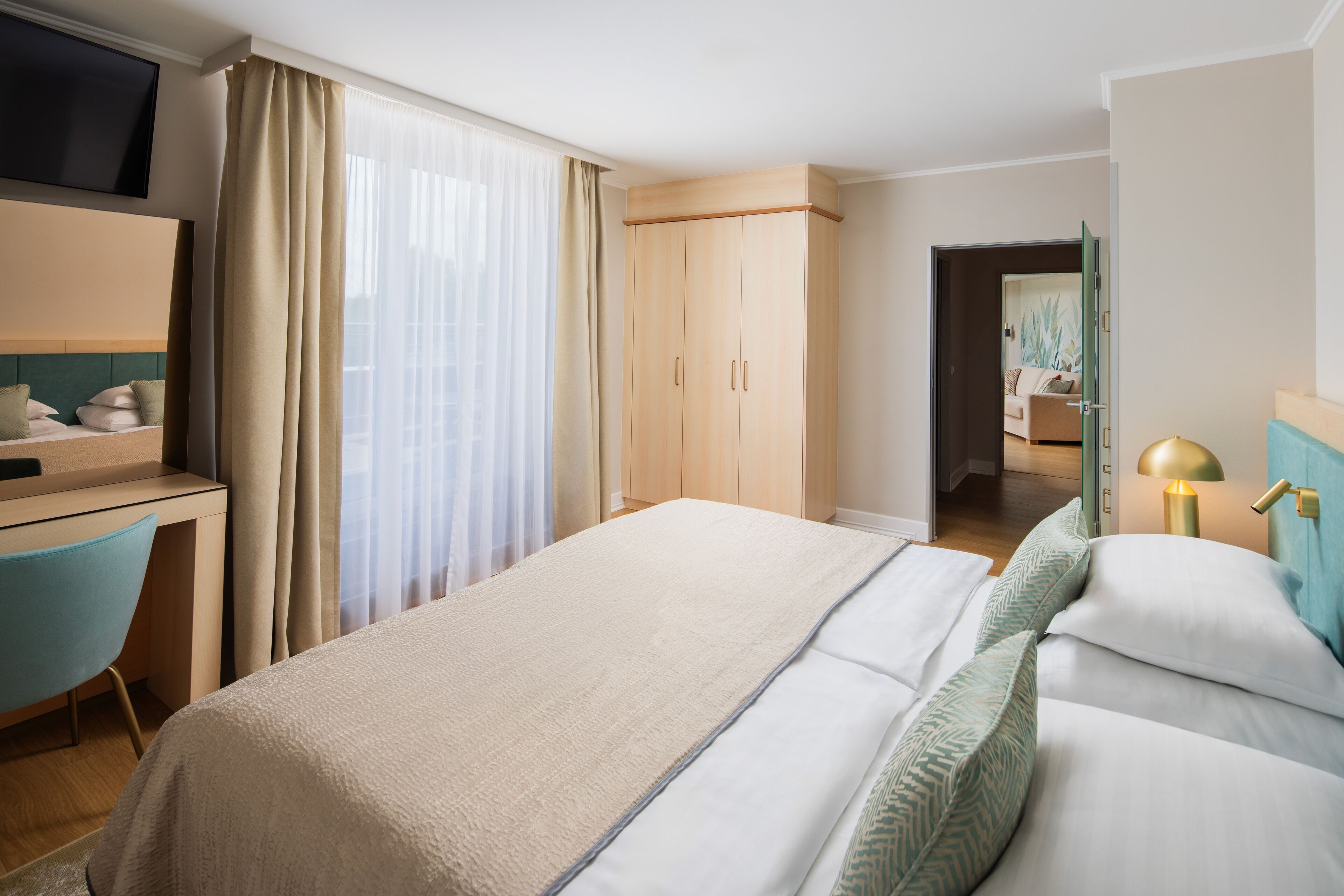 A hotel room with a bed, a desk, a TV, and a wardrobe.