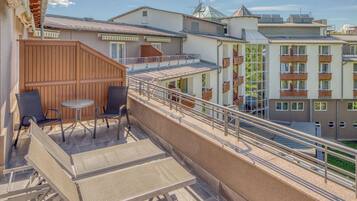 A balcony with outdoor seating, a staircase, and a view of adjacent buildings.