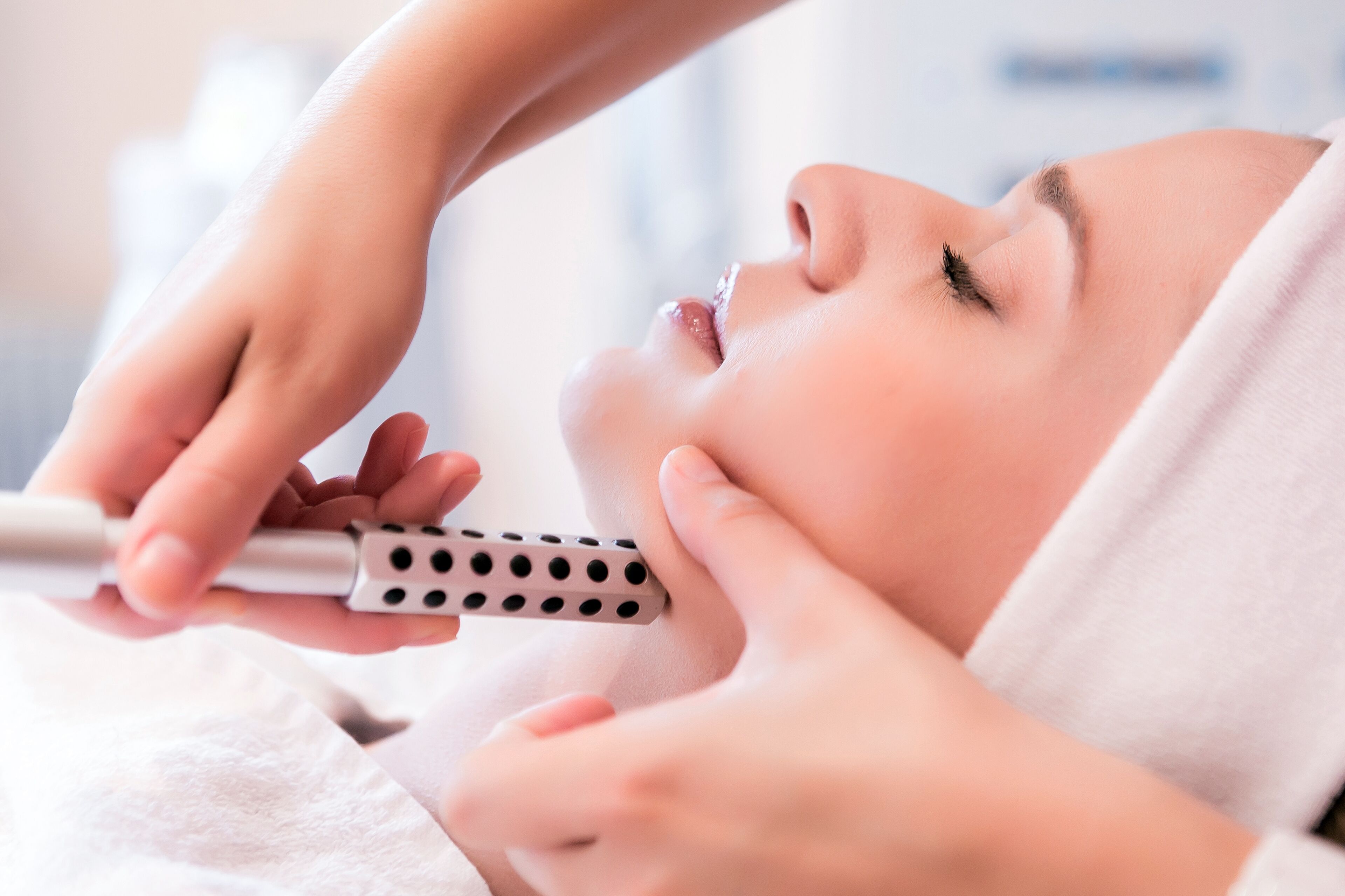 A person lying down with a device being used on their face.